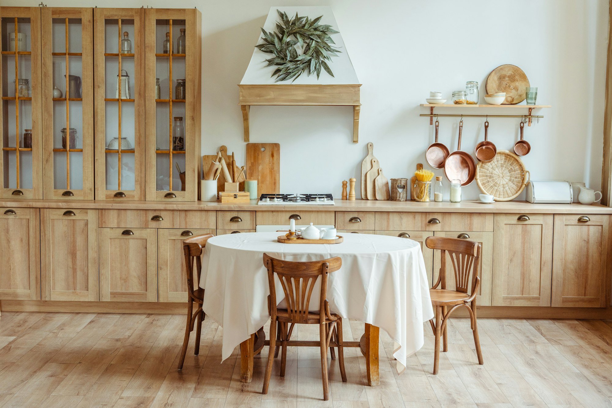 Farmhouse kitchen with timber glass-door cabinets, hanging copper pans and a round table
